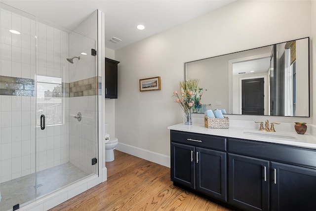 bathroom featuring a shower with door, toilet, vanity, and hardwood / wood-style floors