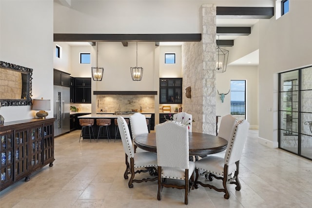 dining space with beam ceiling, light tile patterned flooring, a notable chandelier, and a high ceiling