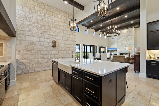 kitchen featuring an island with sink, sink, beam ceiling, wooden ceiling, and decorative light fixtures