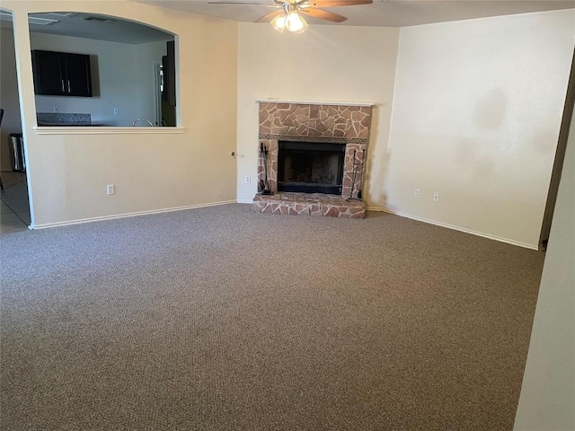 150 Spring Branch Dr, Kyle, TX 78640 - unfurnished living room featuring a ceiling fan, carpet floors, baseboards, and a stone fireplace