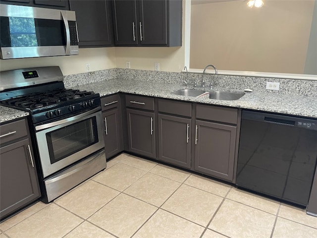 kitchen with sink, appliances with stainless steel finishes, light stone counters, and light tile patterned floors