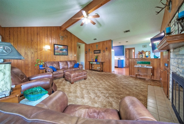 carpeted living room with ceiling fan, a fireplace, a textured ceiling, and vaulted ceiling with beams