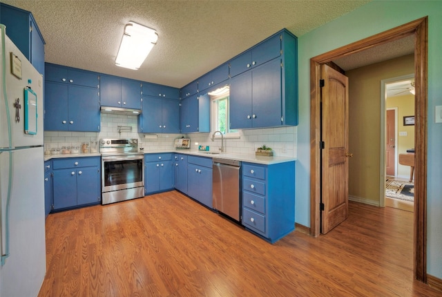 kitchen featuring stainless steel appliances, blue cabinetry, and light wood-type flooring