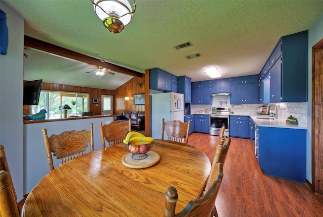 dining space featuring a textured ceiling, dark hardwood / wood-style flooring, sink, ceiling fan, and vaulted ceiling with beams