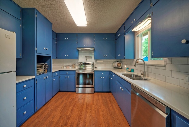 kitchen featuring backsplash, stainless steel appliances, sink, dark hardwood / wood-style floors, and blue cabinets