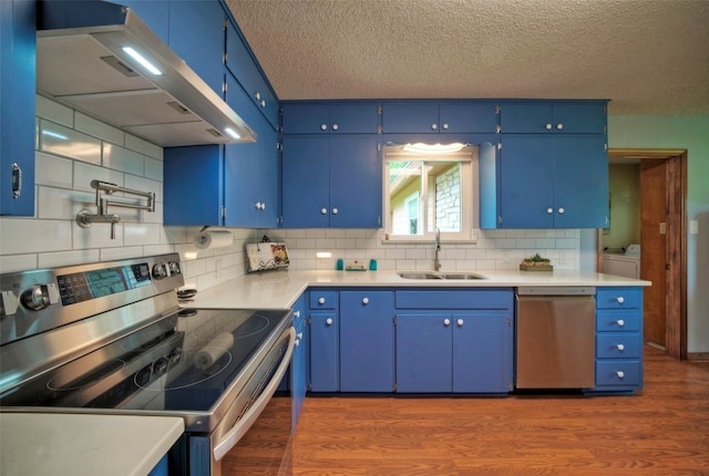 kitchen featuring washing machine and clothes dryer, stainless steel appliances, sink, and blue cabinetry