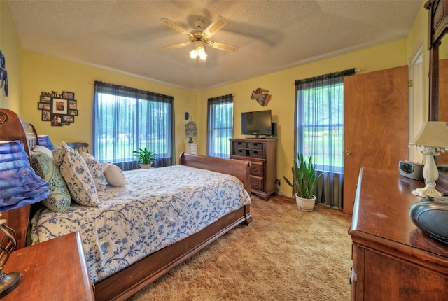 bedroom with a textured ceiling, ceiling fan, and light carpet