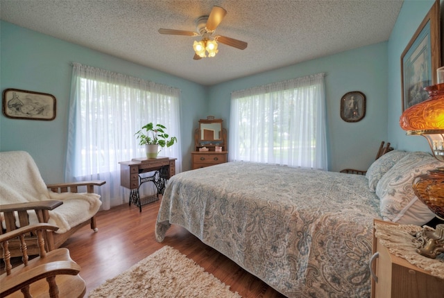 bedroom featuring hardwood / wood-style floors, ceiling fan, and a textured ceiling