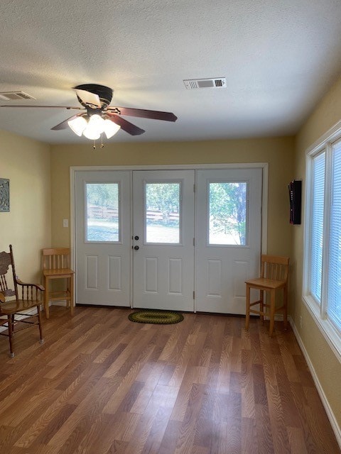 foyer entrance featuring ceiling fan, a textured ceiling, wood-type flooring, and a healthy amount of sunlight