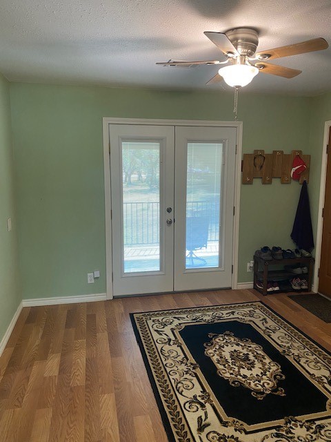 doorway with ceiling fan, hardwood / wood-style flooring, a textured ceiling, and french doors