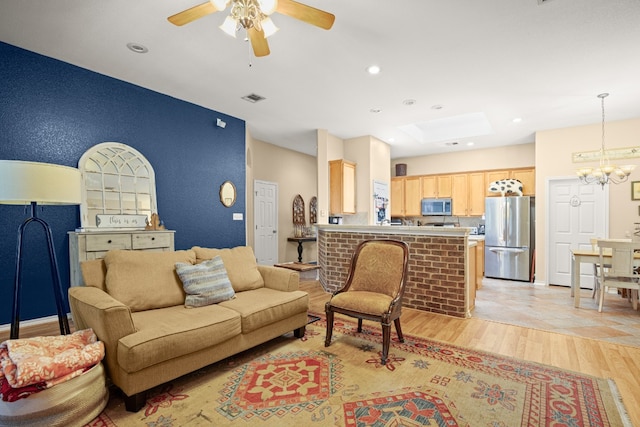 tiled living room with ceiling fan with notable chandelier