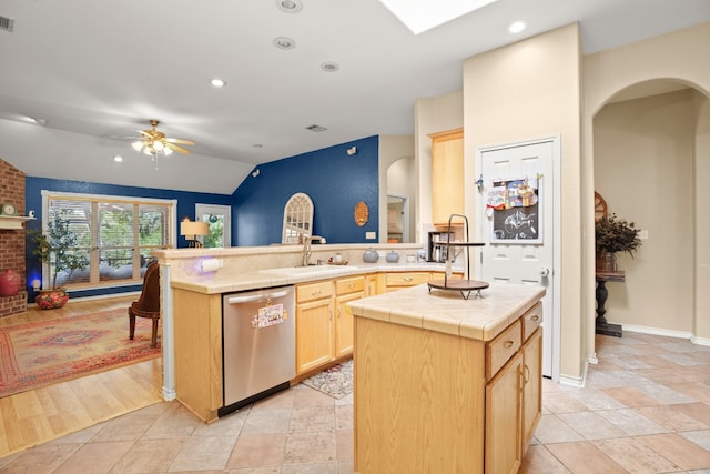 kitchen with light wood-type flooring, a center island with sink, kitchen peninsula, and stainless steel dishwasher