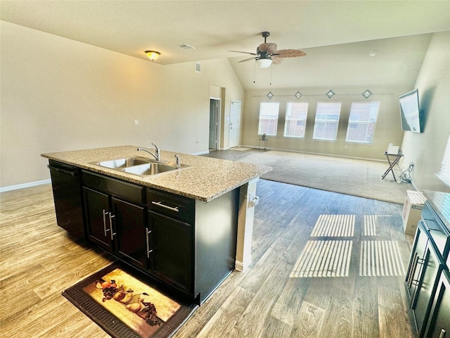 kitchen with black dishwasher, lofted ceiling, light hardwood / wood-style floors, and a center island with sink