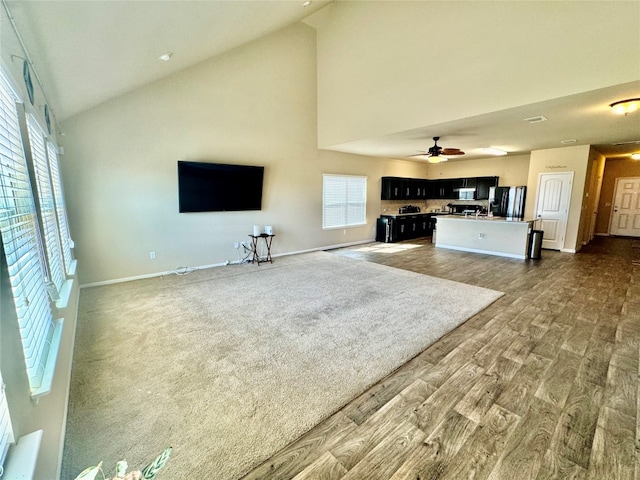 living room featuring hardwood / wood-style flooring, high vaulted ceiling, and ceiling fan