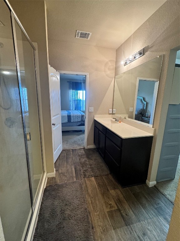 bathroom featuring vanity, a textured ceiling, a shower with shower door, and wood-type flooring