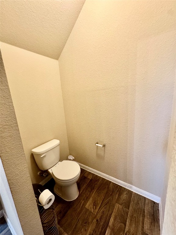 bathroom featuring lofted ceiling, a textured ceiling, wood-type flooring, and toilet