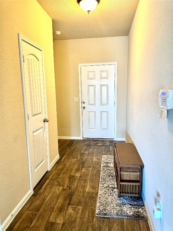 hallway with a textured ceiling and dark wood-type flooring