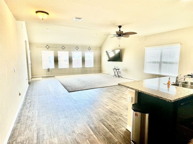 interior space with sink, ceiling fan, hardwood / wood-style flooring, and vaulted ceiling