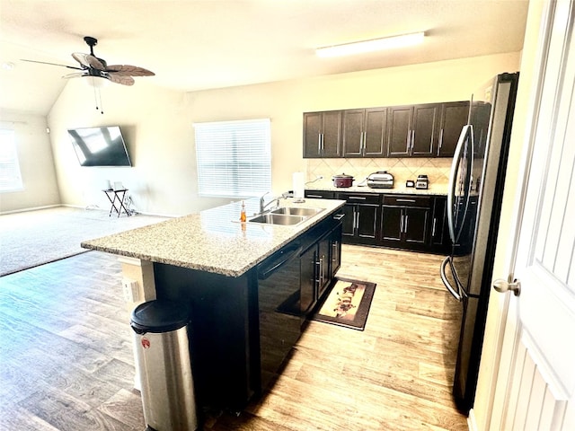 kitchen with dishwasher, a center island with sink, sink, stainless steel fridge, and light hardwood / wood-style floors