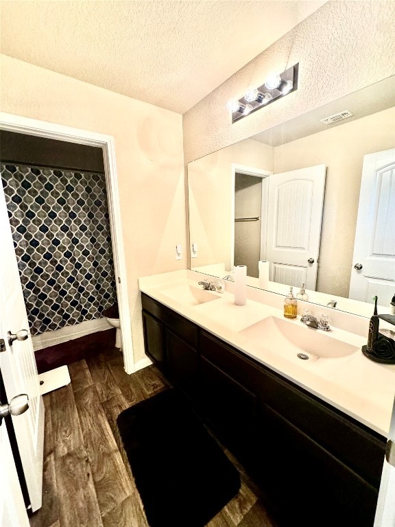 bathroom featuring vanity, a textured ceiling, toilet, and wood-type flooring