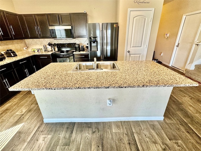 kitchen featuring light hardwood / wood-style floors, electric range, an island with sink, and stainless steel fridge