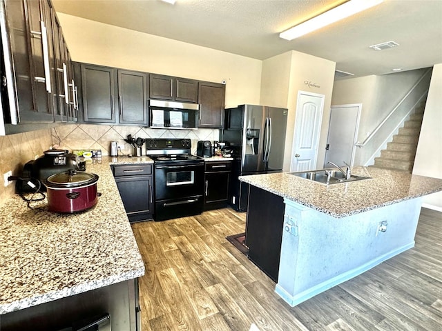 kitchen with sink, light wood-type flooring, dark brown cabinets, stainless steel appliances, and a breakfast bar area