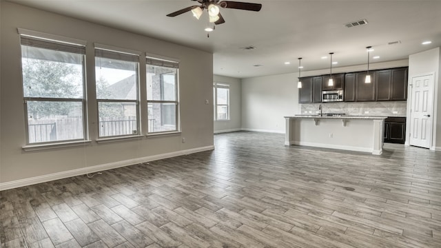 unfurnished living room featuring ceiling fan and wood-type flooring