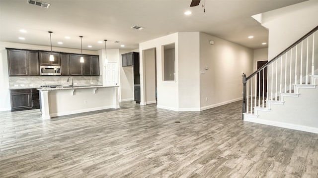 unfurnished living room with sink, ceiling fan, and light hardwood / wood-style floors