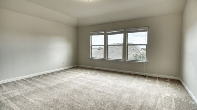 spare room featuring lofted ceiling and light colored carpet