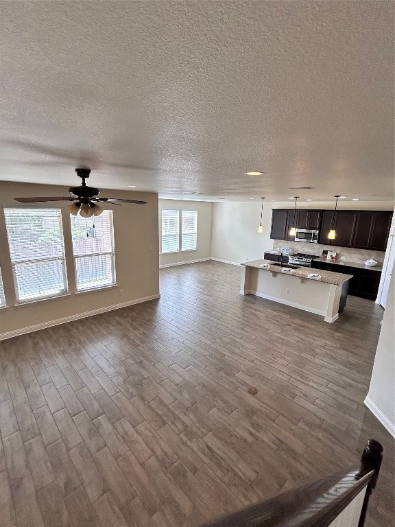 unfurnished living room with ceiling fan, dark hardwood / wood-style flooring, and sink