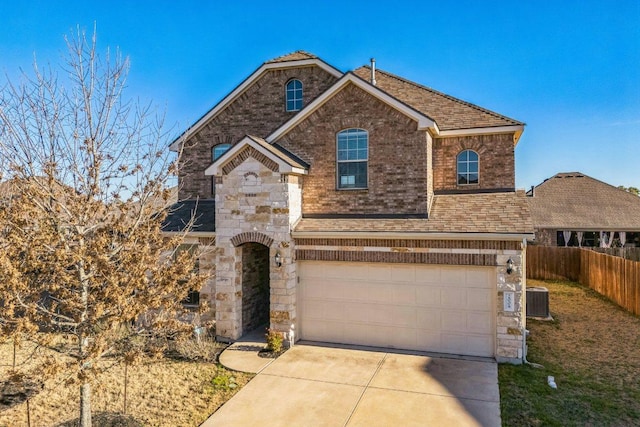 traditional-style house with fence, concrete driveway, roof with shingles, stone siding, and an attached garage