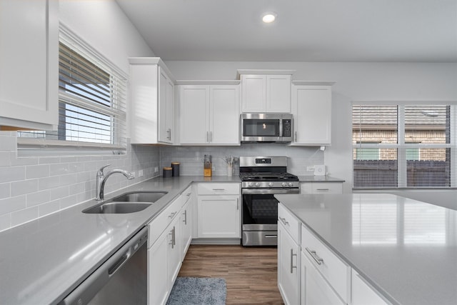 kitchen with sink, tasteful backsplash, dark hardwood / wood-style flooring, white cabinets, and appliances with stainless steel finishes