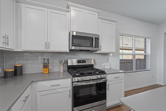 kitchen featuring white cabinets, appliances with stainless steel finishes, and hardwood / wood-style flooring