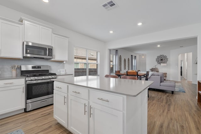 kitchen featuring appliances with stainless steel finishes, light hardwood / wood-style flooring, and white cabinetry