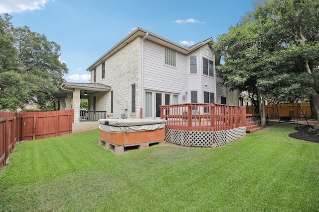 rear view of house featuring a yard, a deck, and a hot tub