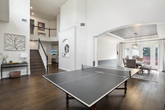 game room with a raised ceiling, a high ceiling, and dark hardwood / wood-style floors