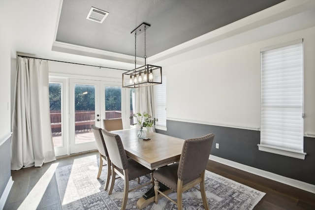 dining space with a tray ceiling, dark hardwood / wood-style flooring, crown molding, and french doors