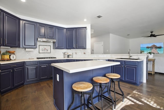 kitchen with a center island, sink, dark wood-type flooring, backsplash, and a breakfast bar area