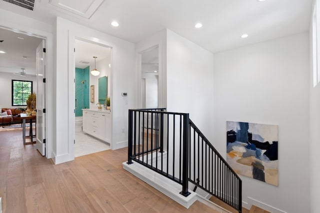 stairs featuring ceiling fan and hardwood / wood-style flooring