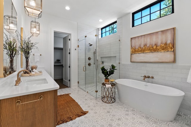 bathroom with tile walls, tile patterned flooring, vanity, and a healthy amount of sunlight