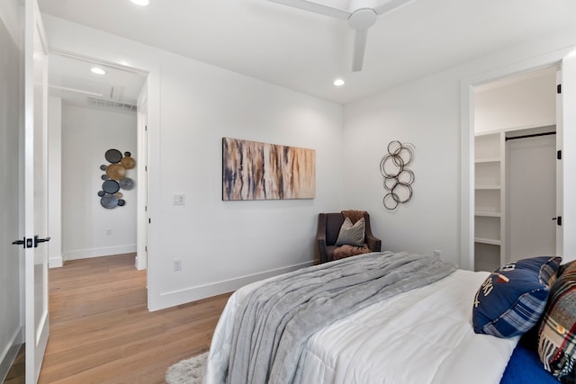 bedroom featuring light hardwood / wood-style floors, a spacious closet, ceiling fan, and a closet