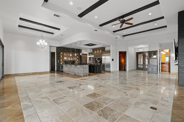 interior space featuring indoor bar, ceiling fan with notable chandelier, a raised ceiling, and a high ceiling