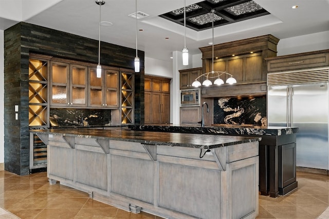 kitchen featuring a spacious island, built in appliances, a kitchen breakfast bar, and decorative light fixtures