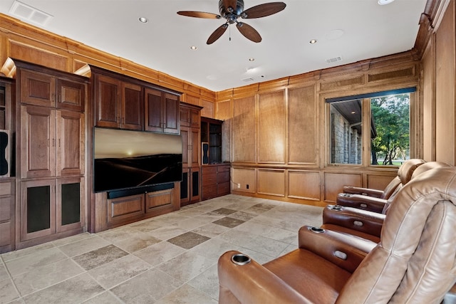 unfurnished living room featuring ceiling fan and wooden walls