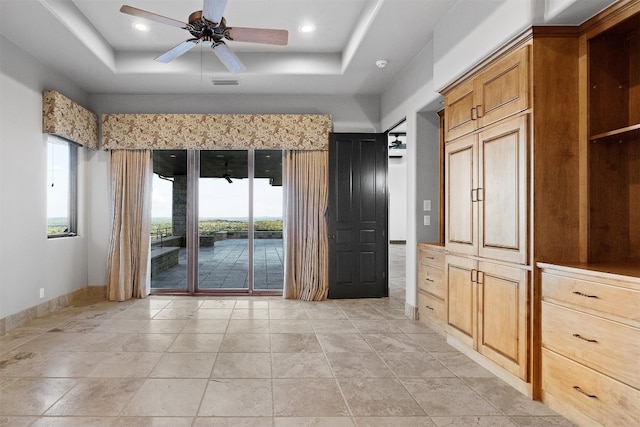 interior space with a raised ceiling and ceiling fan