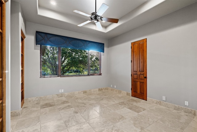 spare room with a raised ceiling and ceiling fan