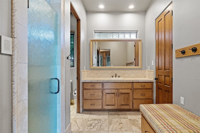 bathroom with vanity, toilet, backsplash, and a shower with shower door