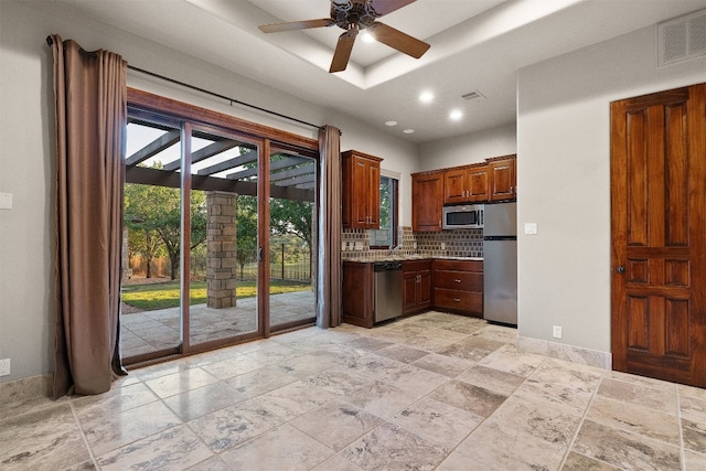 kitchen featuring tasteful backsplash, ceiling fan, appliances with stainless steel finishes, and a tray ceiling