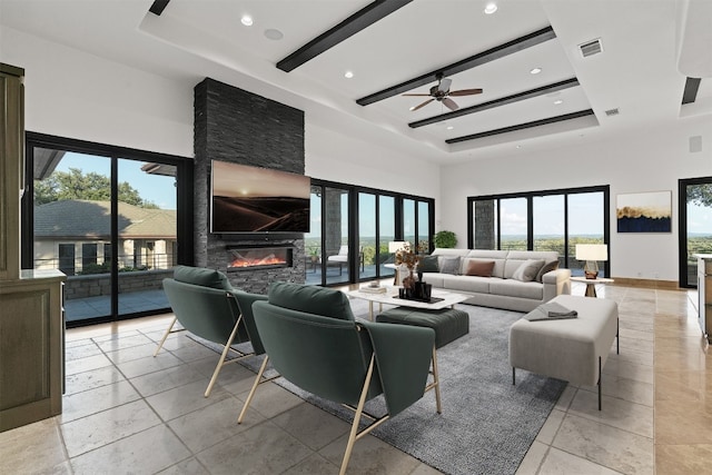 living room with a raised ceiling, ceiling fan, a high ceiling, and a fireplace