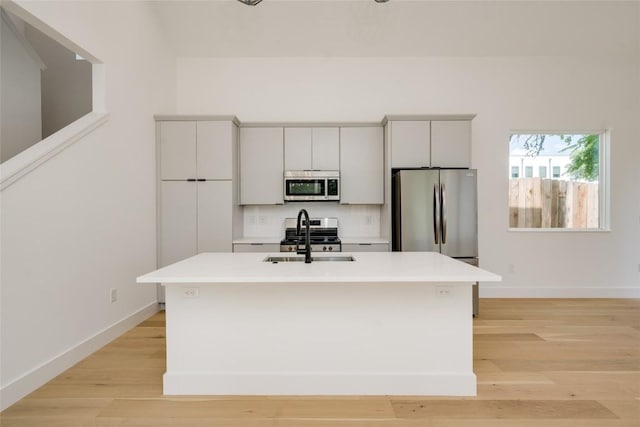 1928 Miles Ave Unit 2, Austin, TX 78745 - kitchen with stainless steel appliances, a sink, light countertops, an island with sink, and light wood-style flooring